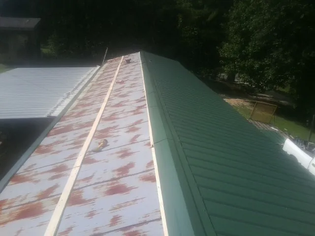 Old rusted panels beside newly installed green metal roofing — Wind Damage Roof Repair by Roofing Brothers in Chesterland