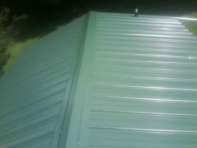New green metal panels meeting at the ridge of a roof — Flat Roof Repair work by our crew in Chesterland
