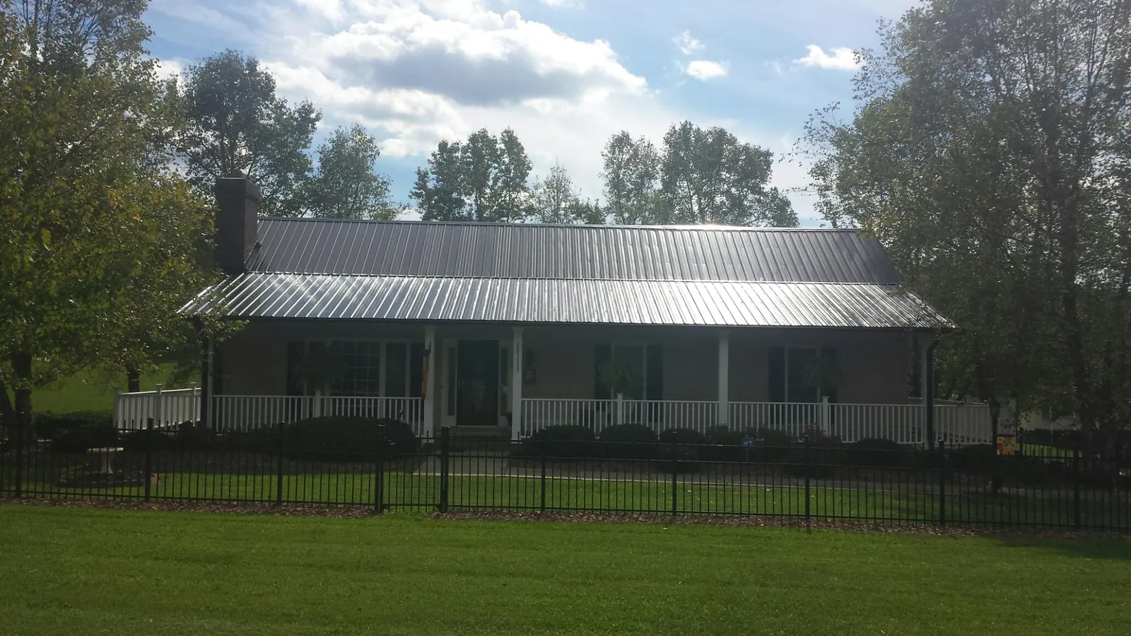 Gray metal roof on a brick ranch with a full width front porch — Gutter Guard Installation work by our crew in Chesterland