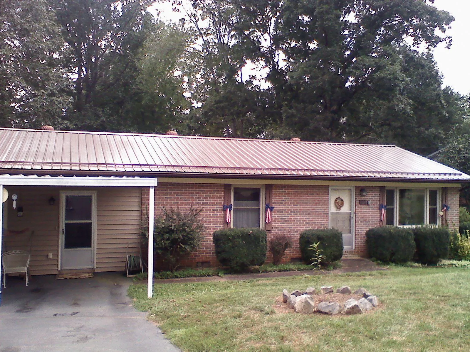 Bronze metal roof and carport on a brick ranch home — Roof Repair work by our crew in Chesterland
