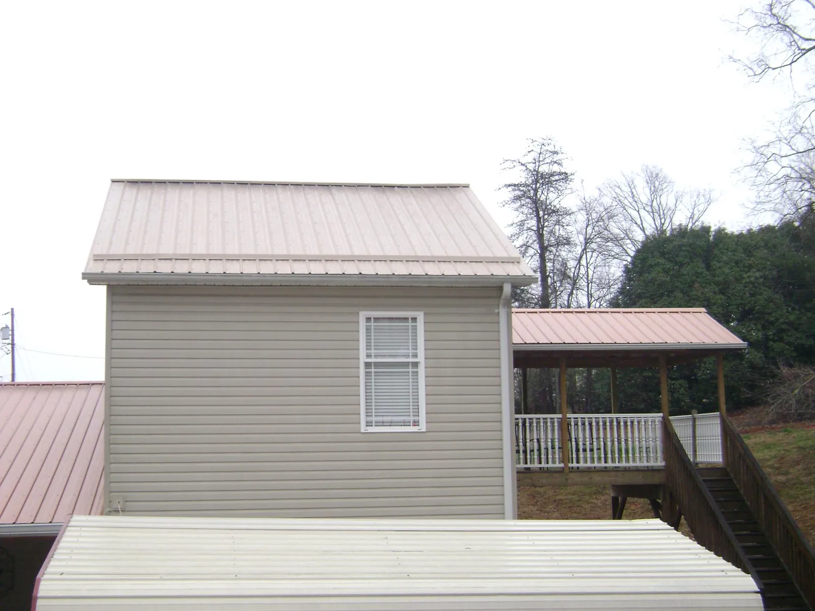 Tan metal roofs on a two story addition and attached porch, from a Roof Replacement job in Chesterland