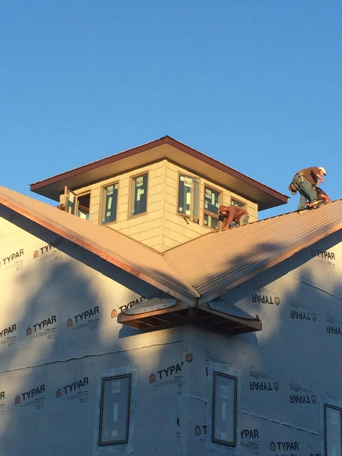 Roofers working around a rooftop cupola on a new metal roof at sunset — Roof Waterproofing in Chesterland by Roofing Brothers